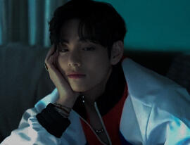 a cool-tinted picture of taehyung gazing softly down at jungkook’s picture beneath him, chin resting in his hand. the image’s border is a circle.